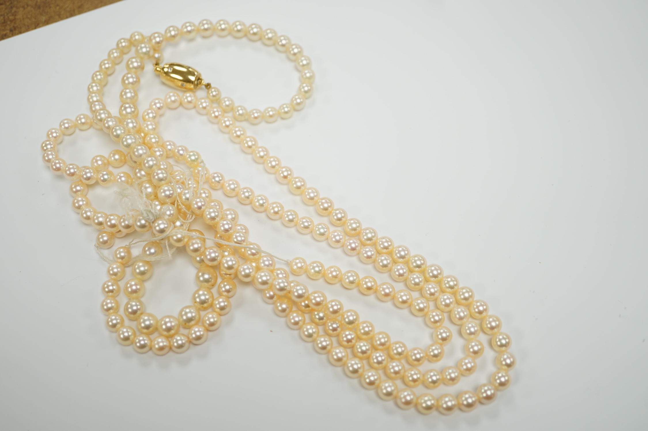 A single? strand cultured pearl necklace, with diamond inset barrel shaped yellow metal clasp (knotted).